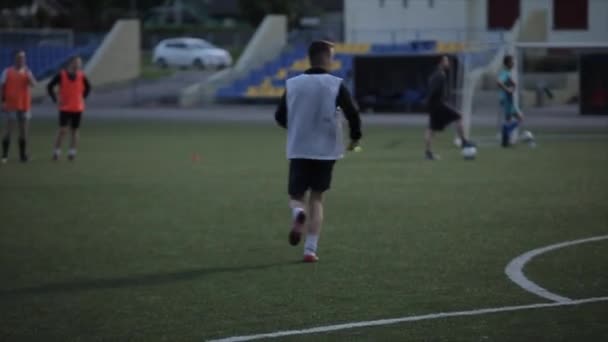 Večerní trénink fotbalového týmu na městském stadionu. Střílí zpoza brány skrz síť. Rozmazané přední pozadí. Detailní záběr — Stock video