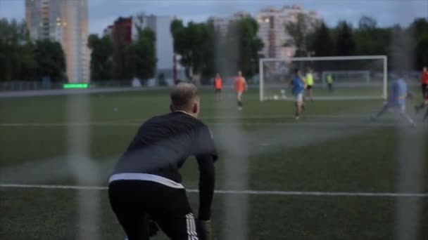 Målmanden sparker bolden på fodboldklubbens træning. Skud fra bag porten. Kameraet skifter fokus. Nærbillede – Stock-video