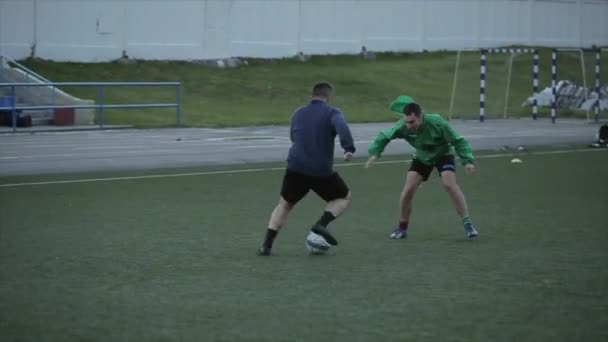 Entrenamiento del equipo de fútbol. Los jugadores realizan ejercicios de velocidad complejos saltando sobre las barreras y corriendo alrededor del campo con la pelota. Primer plano — Vídeo de stock