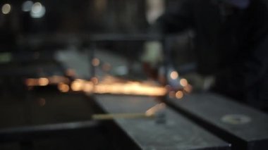 Atölyede koyu bir arka planda metal öğütülürken elektrikli öğütücüden çıkan bulanık arka plan kıvılcımları