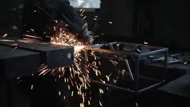 Jiskry z elektrického brusného nástroje vyletí zpod rukou zámečníka při zpracování kovu v dílně. Detailní záběr. Pohled zezadu — Stock video