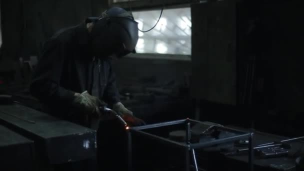 Helder blauw licht van lassen. Een man met een lasmasker werkt in de werkplaats met metalen constructies. Uitzicht vanaf de zijkant. Close-up — Stockvideo