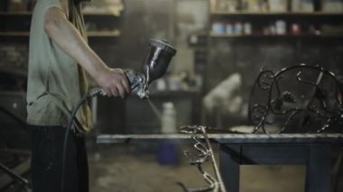 Demircide dövülmüş sanat öğeleri olan hazır üretim sahte bir ürünün elektrikli spreyinin yakın çekimi.