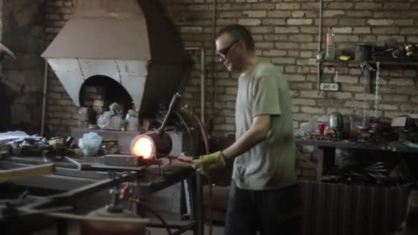 赤熱線での操作。鍛冶屋はオーブンから鉄の棒を取り出し、まだ熱いうちに曲げます。サイドビュー — ストック動画