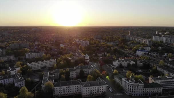 Pomalý letecký záběr na velkou část města topící se v zeleni a panorama zapadajícího slunce — Stock video
