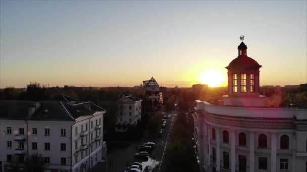 Natáčení z drone části města s krásnou starou budovou s věží, přes kterou paprsky západu slunce — Stock video