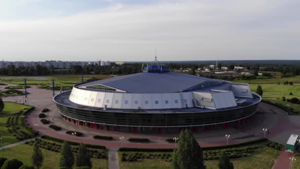 Légi kilátás nyílik a kupola a kerek jég aréna a zöld övezetben a város panorámája ellen. Lassú lövés. — Stock videók