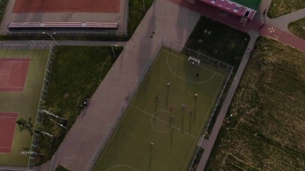 Una vista de pájaro del campo de deportes y la gente que juega al fútbol en la zona deportiva de la ciudad. Efecto de giro cámara — Vídeos de Stock