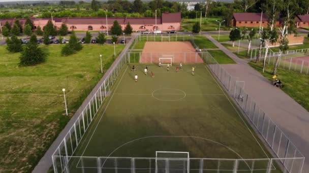 Disparos desde la altura de un partido de fútbol en un campo de deportes al aire libre junto al aparcamiento de coches y edificios de la ciudad — Vídeos de Stock