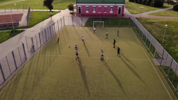 Los jóvenes juegan fútbol amateur en el campo de deportes de la ciudad. Disparando desde un helicóptero. La cámara se acerca lentamente. Primer plano — Vídeos de Stock