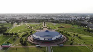 Kuşbakışı büyük gümüş bir buz arenasının kubbesini yeşil çimlerin ve ara sokakların arasında şehrin manzarası. Yavaş çekim.