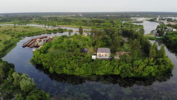 Panoráma a folyó partján a régi uszályok közelében a folyó zöld sziget hátterében a kikötői daruk és a vasúti híd. Lassú légi felvétel. — Stock videók