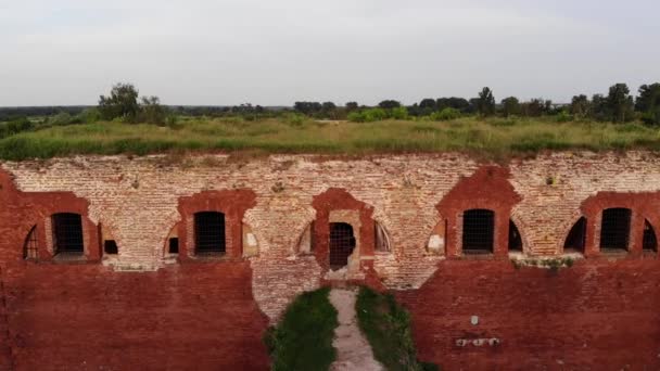 View from above to the dilapidated bastion of the ancient fortress and river bank with houses and rusty barges by the shore in the bay — Stock Video