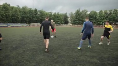 Futbol kulübünün sporcuları futbol sahasında antrenman yapıyor. Maçta birbirlerine pas veriyorlar. Yakın plan.