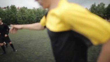 Futbol kulübü antrenmanında bir maç anı. Sporcu, topu kaçıran ortağın omzuna hafifçe vurmasını destekler. Yakın plan.