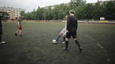 Bulutlu bir yaz gününde stadyumda futbol antrenmanı. Kamera topu takip eder. Yakın plan.