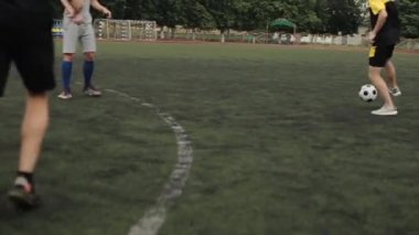 Futbol antrenmanındaki futbolcular futbol sahasında oyun anlarında çalışırlar. Kamera topu takip eder. Yakın plan.