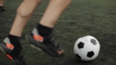Antrenman sırasında stadyumda futbol oynayan atletlerle bacakların yakın çekimi. Yavaş çekim