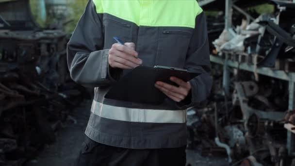 Joven mecánico de automóviles hace inventario en el almacén de piezas de repuesto. Primer plano. La cámara se mueve de abajo hacia arriba — Vídeo de stock