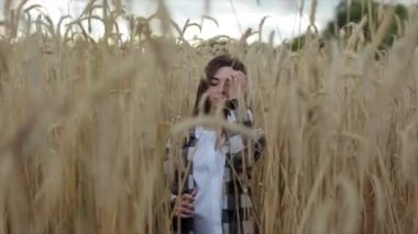 Çekici bir genç kız buğday tarlasında yürüyor. Yakın plan. Yavaş çekim