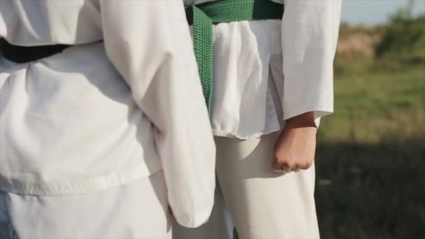 Dos atletas femeninas se paran una frente a la otra en un combate de karate con los puños cerrados. Primer plano de las manos. Cámara zoom dentro y fuera — Vídeos de Stock