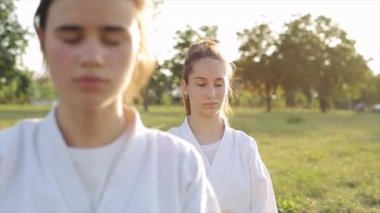 Genç bir kız, karate dersinde meditasyon yaparken kameraya bakar diğeri ise gözleri kapalı oturmaya devam eder. Yakın plan. Ağır çekim. Kamera odağı değiştirir.