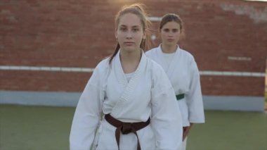 Spor sahasında karate eğitiminde iki genç kadın Kyokushinkai tekniklerini gösteriyor. Ön manzara. Yakın plan. Yavaş çekim