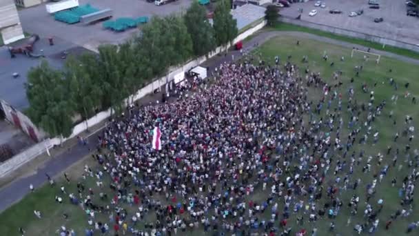 Misk, Belarus - 25 augustus 2020: Filmen vanuit de lucht van een vreedzame betoging voor de vrijheid en onafhankelijkheid van Belarus. Mensen zwaaien met wit-rood-witte vlaggen. Uitzicht vanaf de zijkant. Camera zoomt in — Stockvideo