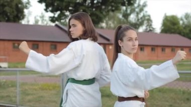 Karate eğitimindeki kadın sporcular Kyokushinkai tekniğinde temel duruş sergiliyorlar. Yakın plan. Ağır çekim. Kamera yakınlaştır