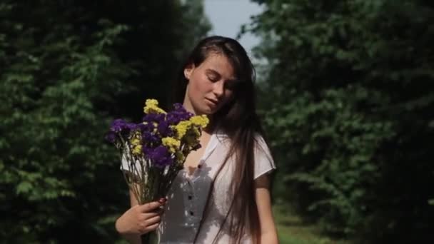 En ung jente i hvit kjole med blomster i hendene i protest mot sikkerhetsstyrkenes handlinger etter presidentvalget i Hviterussland. Nære på. Langsom bevegelse – stockvideo