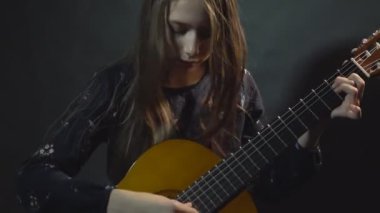Kız oyun gitar. Stüdyo ışık. Koyu arka plan.