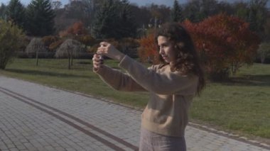Kız parkta selfie çekiyor. 