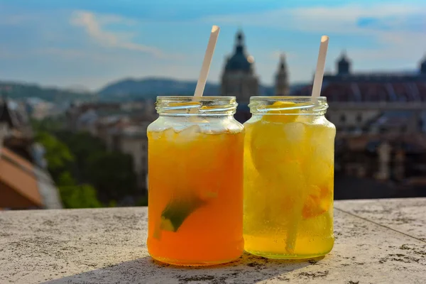 Cocktail glasses with refreshing lemonade on table in rooftop bar against city view. Beautiful rooftop bar in Budapest, Hungary