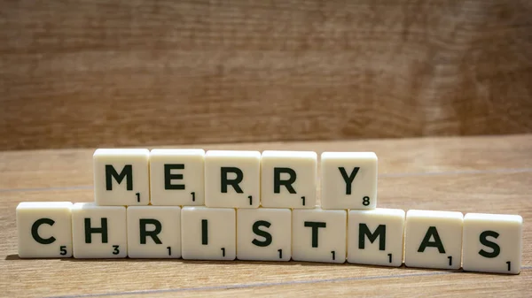 MERRY CHRISTMAS palabra escrita en bloques de madera sobre fondo marrón . —  Fotos de Stock
