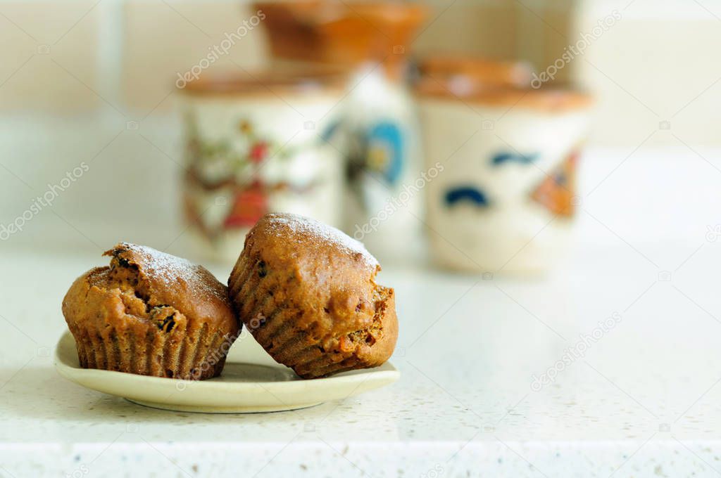 Two muffins with dried fruits and powdered sugar.