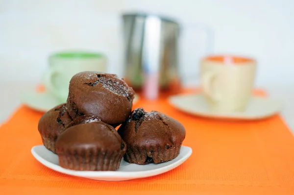 Magdalenas de chocolate en un platillo dos tazas de café y una jarra . — Foto de Stock