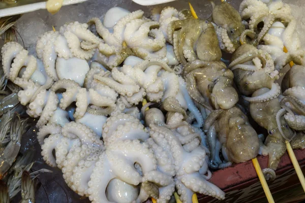 Traditionele zeevruchten, octopus op een sateprikker in de winkels. — Stockfoto