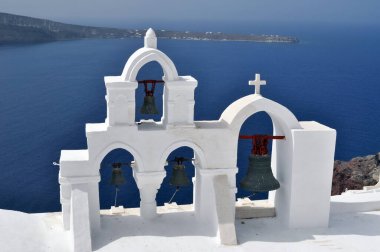 Yunanistan 'ın Santorini kentinin mavi denizinin arka planında çanları olan beyaz şapel