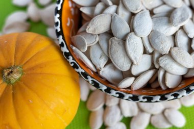 Üst manzara beyaz kabak tohumları bir kasede, arka planda.