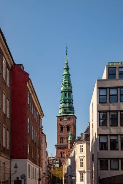 old tower with tall spire and historical buildings on street in copenhagen, denmark