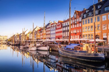 COPENHAGEN, DENMARK - MAY 6, 2018: picturesque view of historical buildings and moored boats reflected in calm water, copenhagen, denmark clipart