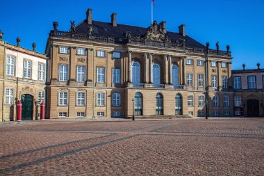 Amalienborg palace on empty street and historical building with statues and columns in copenhagen, denmark clipart