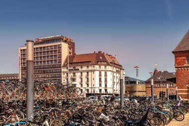 COPENHAGEN, DENMARK - MAY 6, 2018: bicycles of parking lot and cityscape behind  clipart