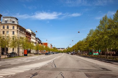COPENHAGEN, DENMARK - MAY 6, 2018: cityscape and road with parked cars  clipart