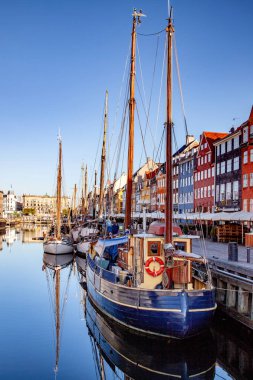COPENHAGEN, DENMARK - MAY 6, 2018: moored boats at harbor near buildings in Copenhagen, Denmark clipart