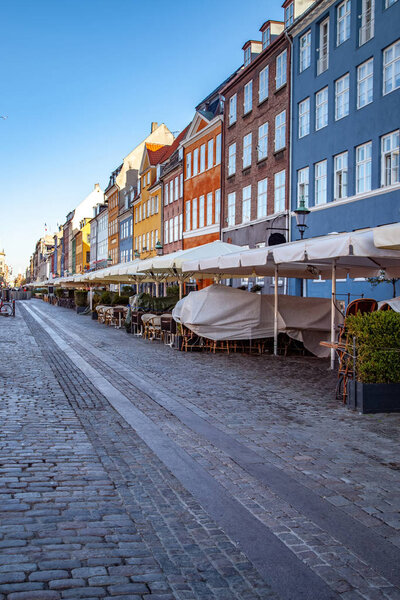 pavement and umbrellas at street cafe near beautiful colorful houses in copenhagen, denmark