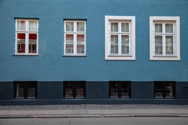 detail of blue and grey building with white windows on street in copenhagen, denmark