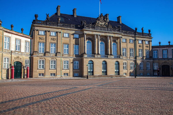 Amalienborg palace on empty street and historical building with statues and columns in copenhagen, denmark