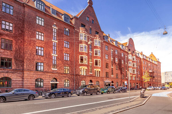 КОПЕНГАГЕН, ДЕНМАРК - 6 мая 2018 года: городской пейзаж со зданиями, автомобилями и пустой улицей
 