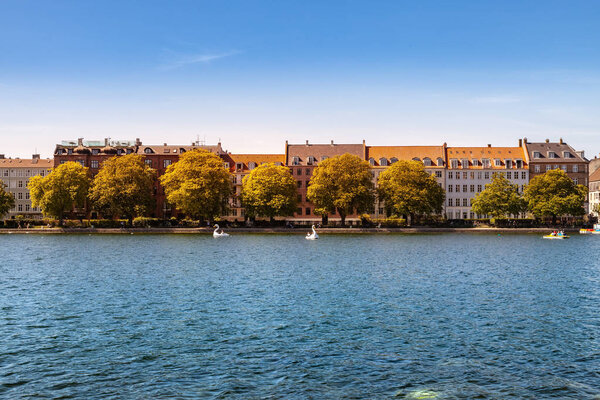 КОПЕНГАГЕН, ДЕНМАРК - 6 мая 2018 года: живописный вид на городской пейзаж, деревья и реку под ясным голубым небом
 
